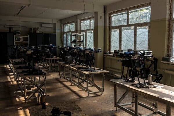 I droni siedono su diversi tavoli in un laboratorio con piccole macchie di luce naturale che si riversano attraverso grandi finestre.