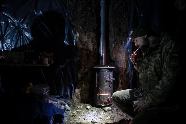Un soldato accende una sigaretta in un bunker sotterraneo con una stufa a tubo.