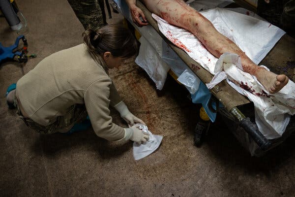 Un medico si prende cura di una persona ferita con la gamba destra insanguinata su una barella.